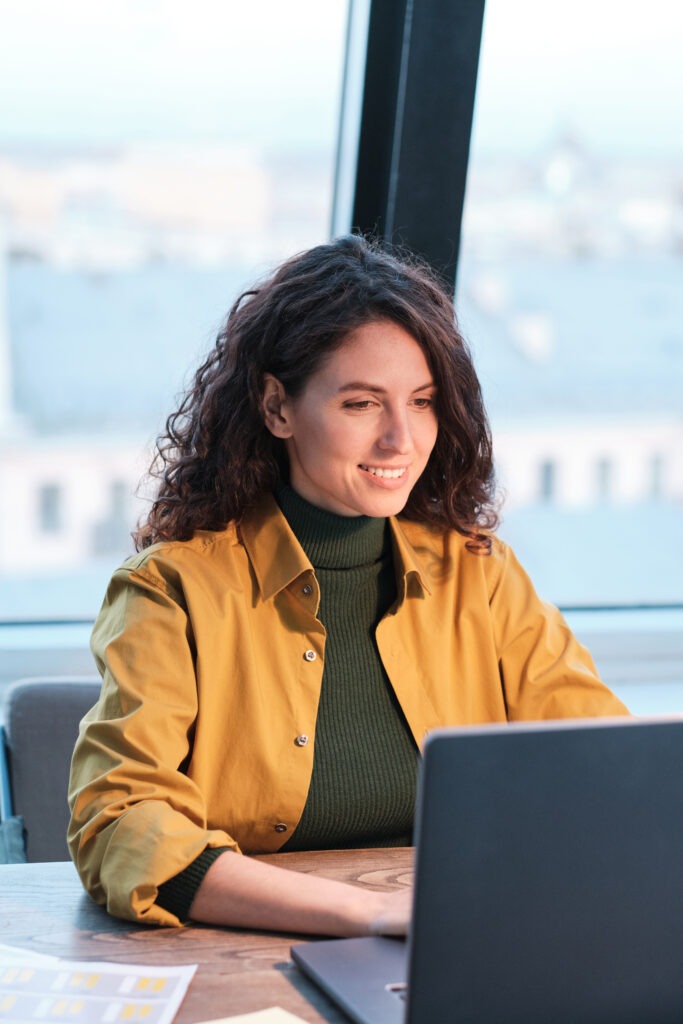 woman in gold color jacket in office at pc